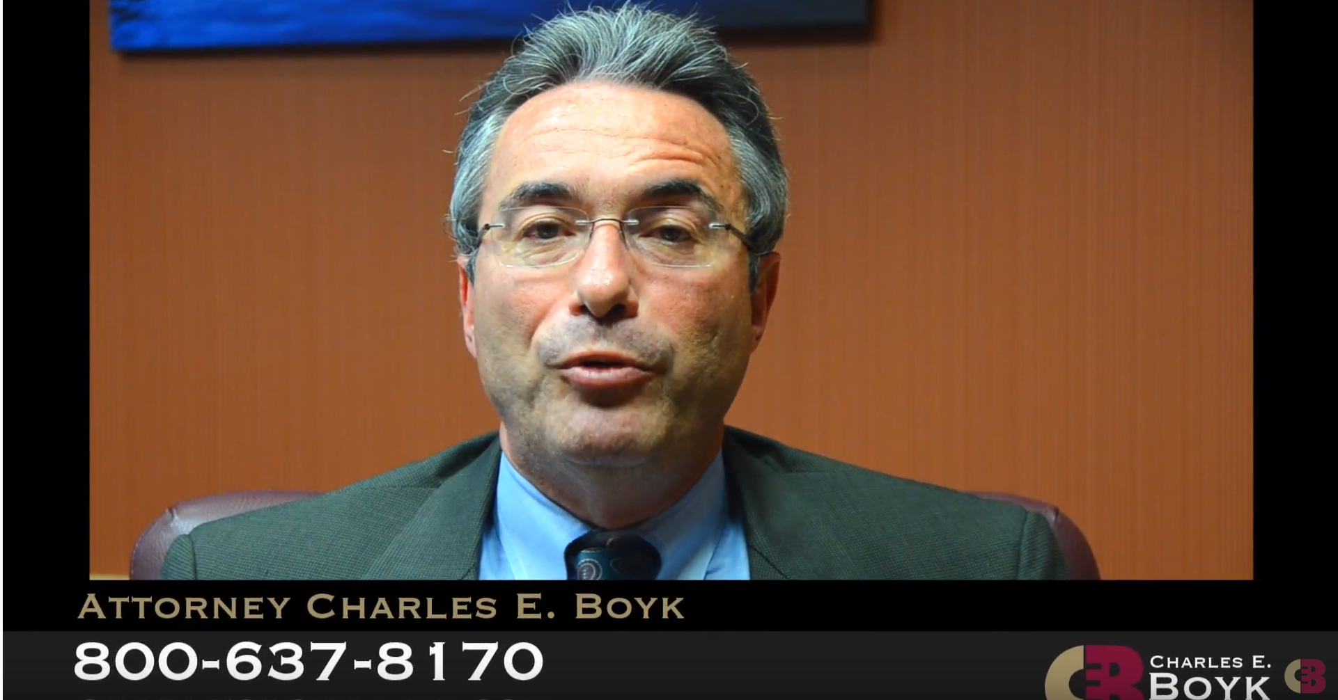 Charles BOyk sitting and speaking and a footer with his name and phone number