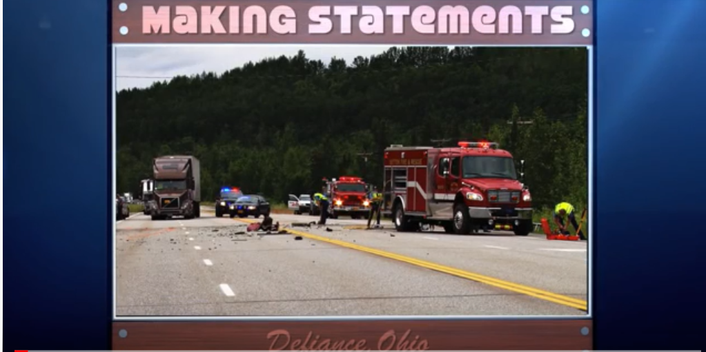 accident scene with fire trucks, police officers and cars, and a sign that says "Making statements"