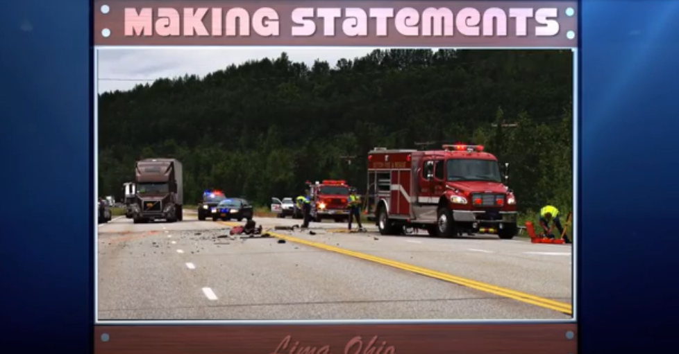 accident scene with fire trucks, police officers and cars, and a sign that says "Making statements"