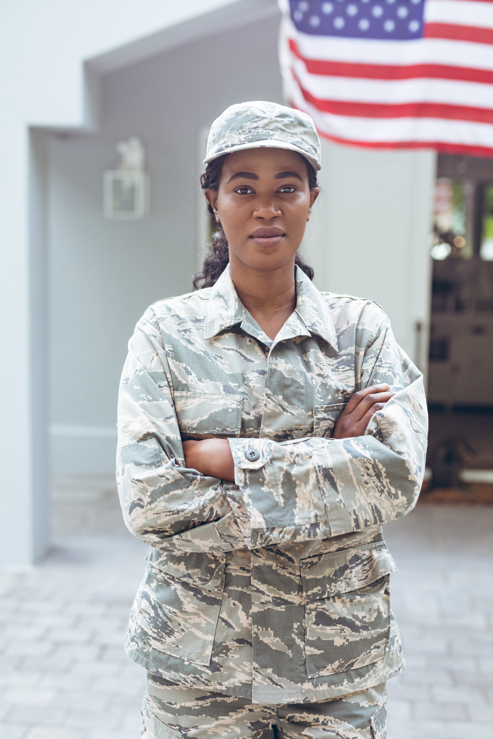 Portrait of confident female mid adult african american soldier in uniform standing outside house. unaltered, pride, military, flag of america, homecoming, armed forces and patriotism concept.