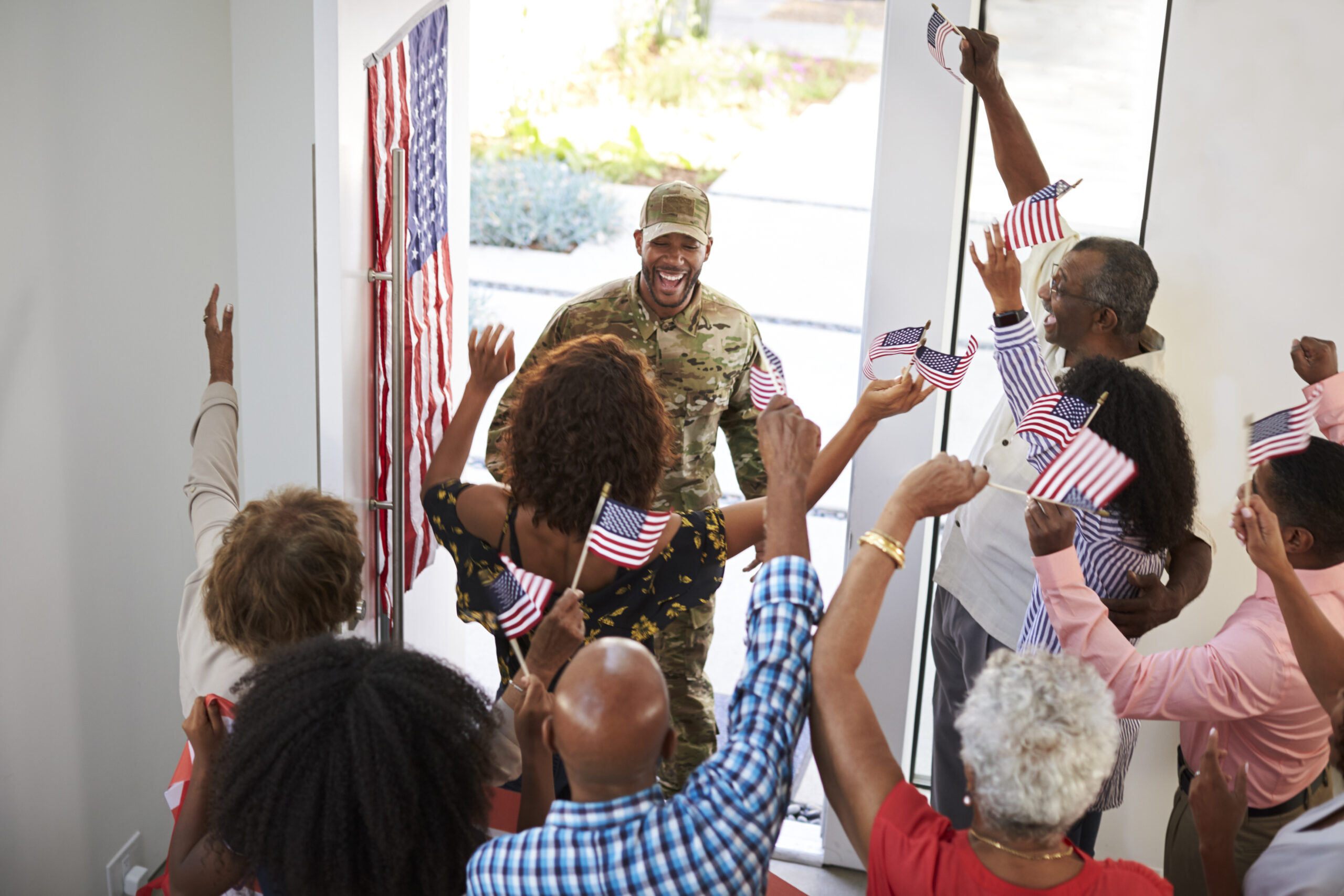 Young black male soldier returning home to his three generation family, elevated view, close up